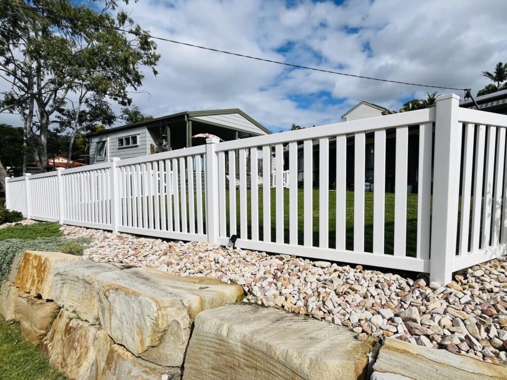Margaret PVC garden fence gallery along a landscaped rock border by Queensland Fencing Specialists